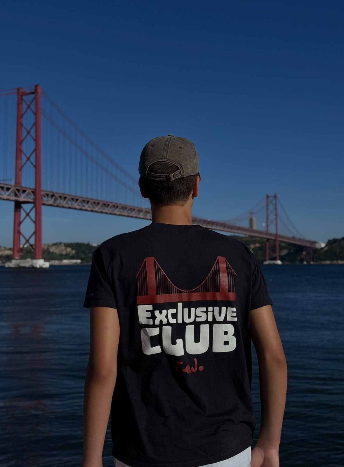 Back of the tee: the 25 de Abril bridge in red above white Exclusive Club lettering.